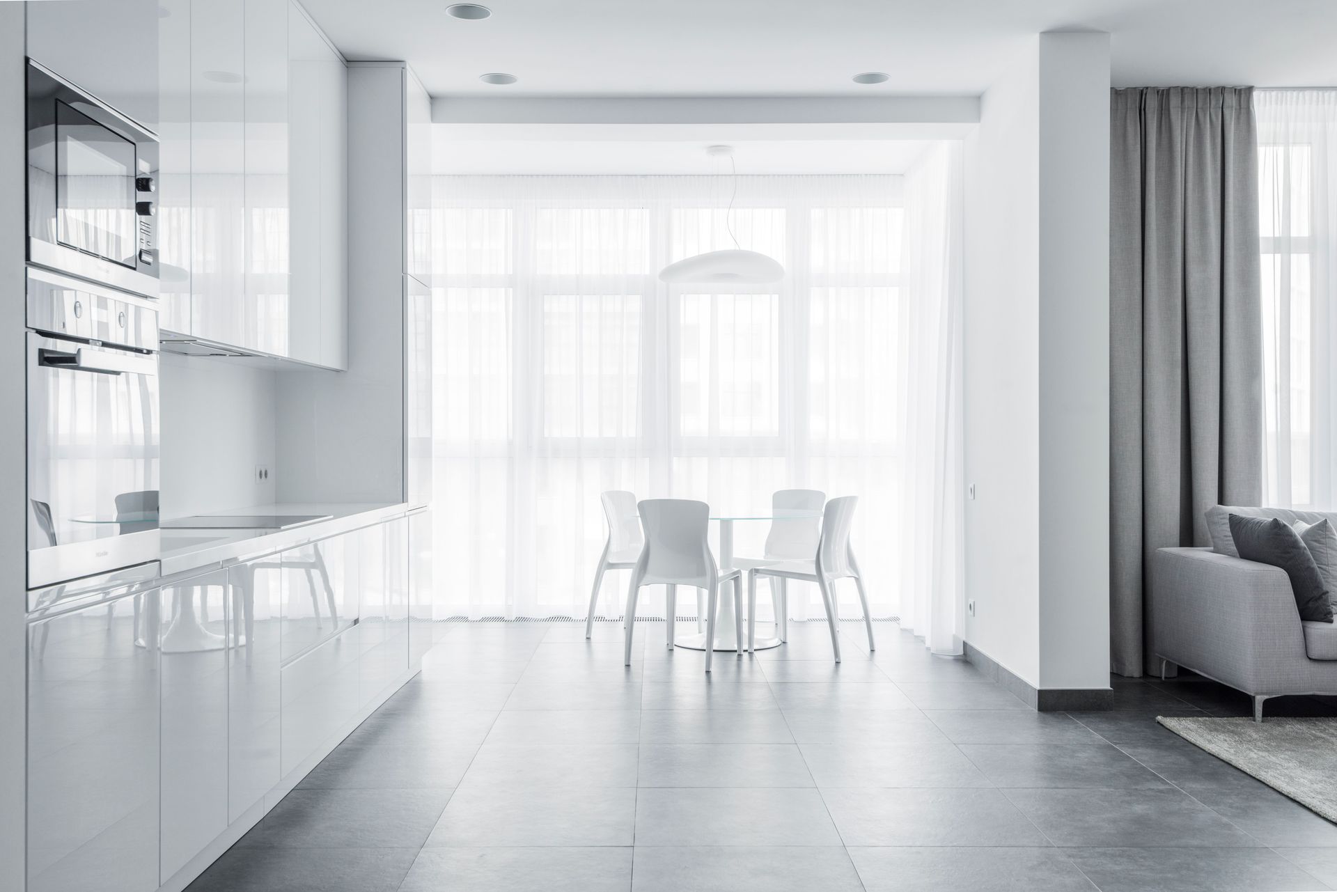 Bright minimalist dining area with white furniture and modern kitchen design.